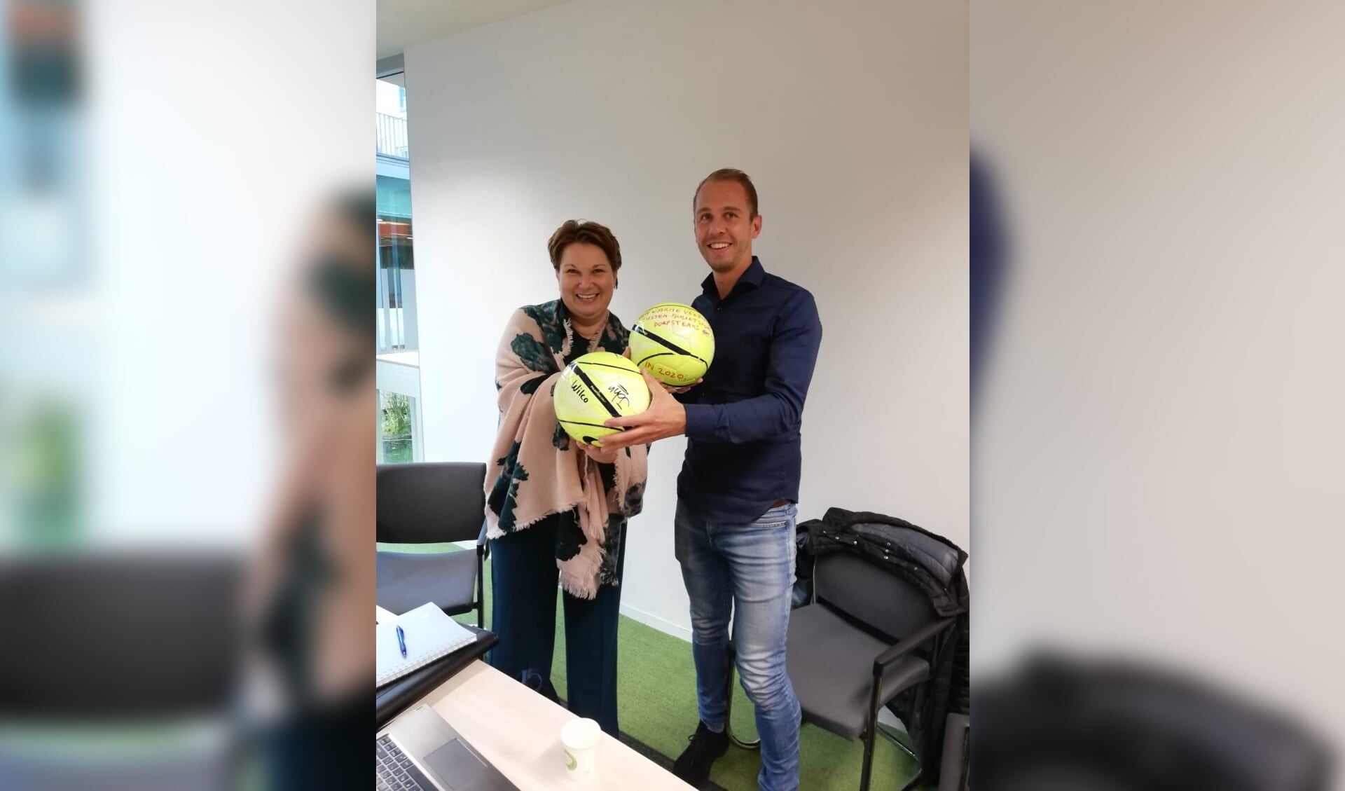 Wethouder Chantal Broekhuis en buurtsportcoach Ruben Buist wisselen ballen uit.
