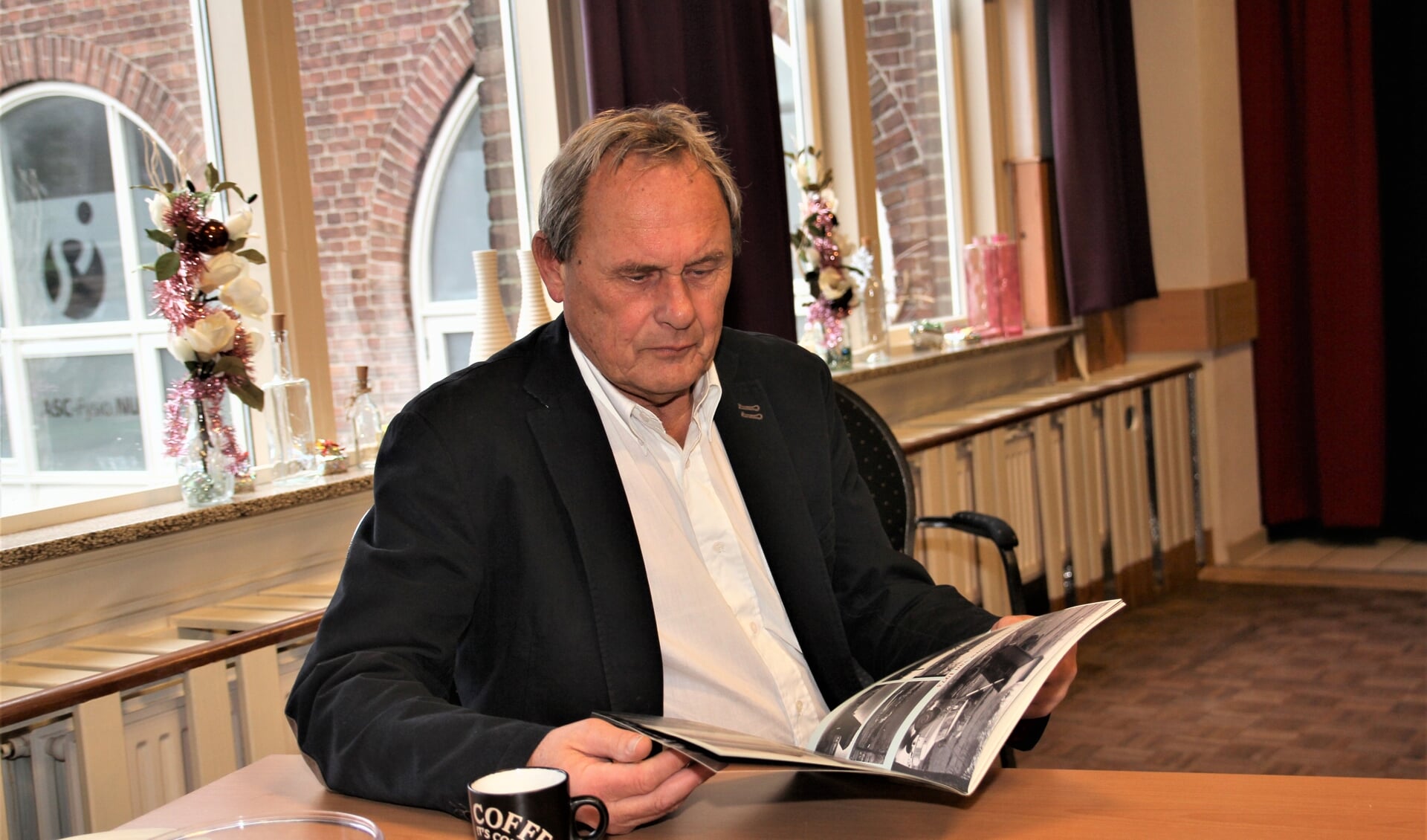 Henk Ruighaver bladert door het jubileumboek.