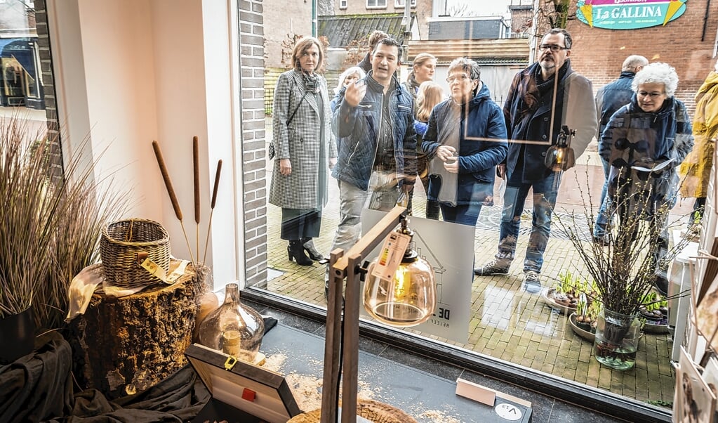 Belangstellenden bekijken een kunstwerk in een etalage tijdens Kunstetalages in 2018.