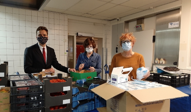 <p>Vanaf links: wethouder Marijn van Ballegooijen, Marja Ernste van de Voedselbank en raadslid Stieneke Kruijer met de doos vol mondkapjes. </p>