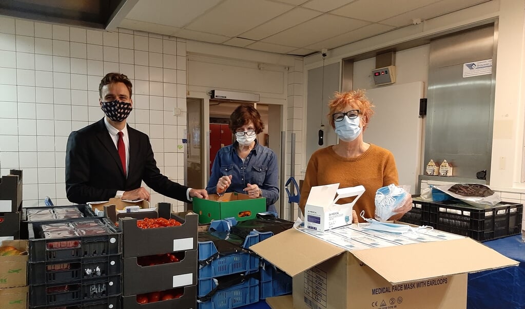 Vanaf links: wethouder Marijn van Ballegooijen, Marja Ernste van de Voedselbank en raadslid Stieneke Kruijer met de doos vol mondkapjes. 