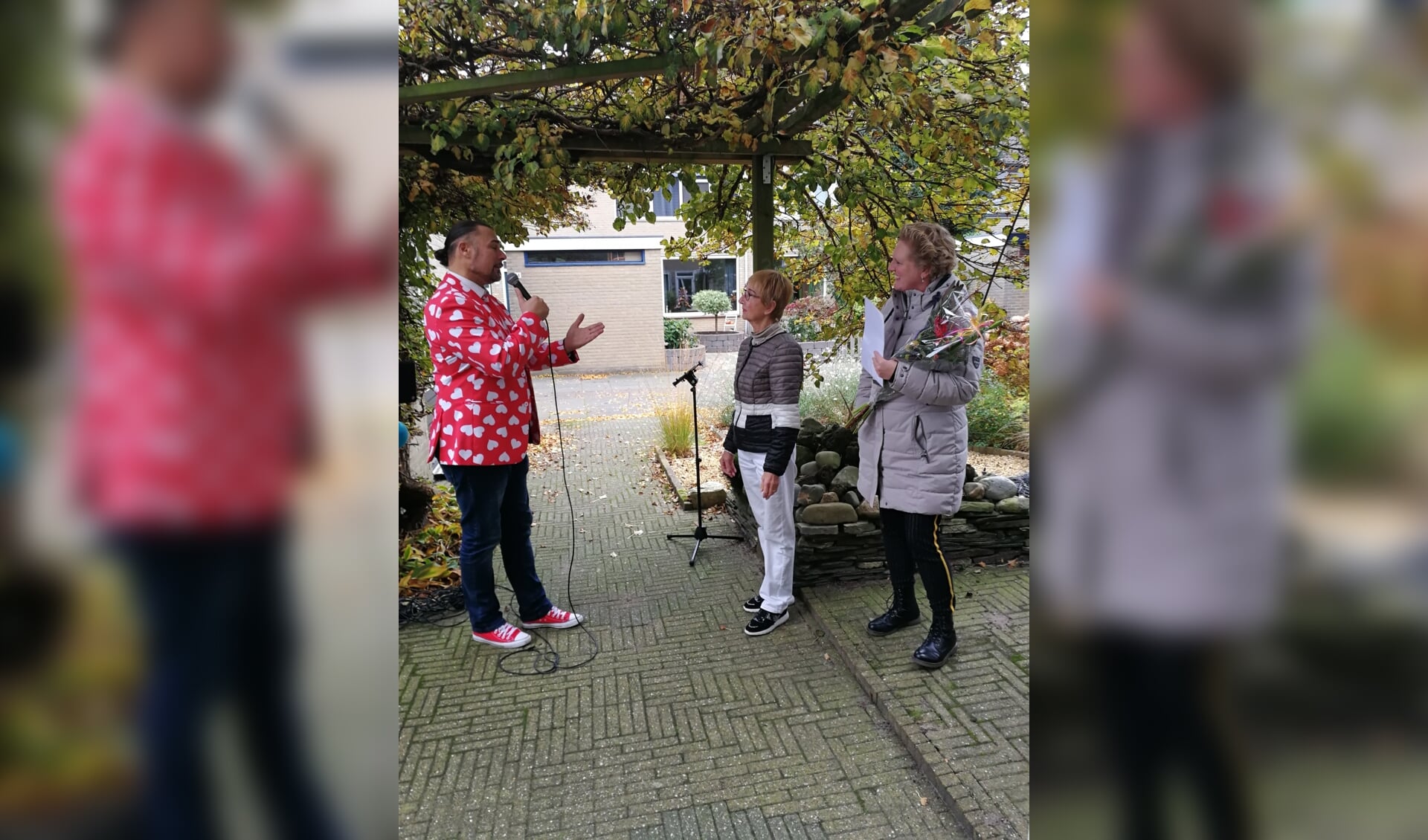 Aubade, bloemen en oorkonde voor jubilerende vrijwilliger Lisidunahof (vlnr Franky Stardust, mw. Alie Maassen van de Brink en Janet de Oude Mooi