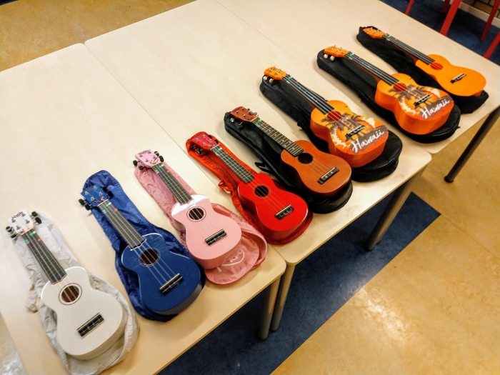 Ukeleles in verschillende maten en kleuren liggen klaar voor de proefles.
