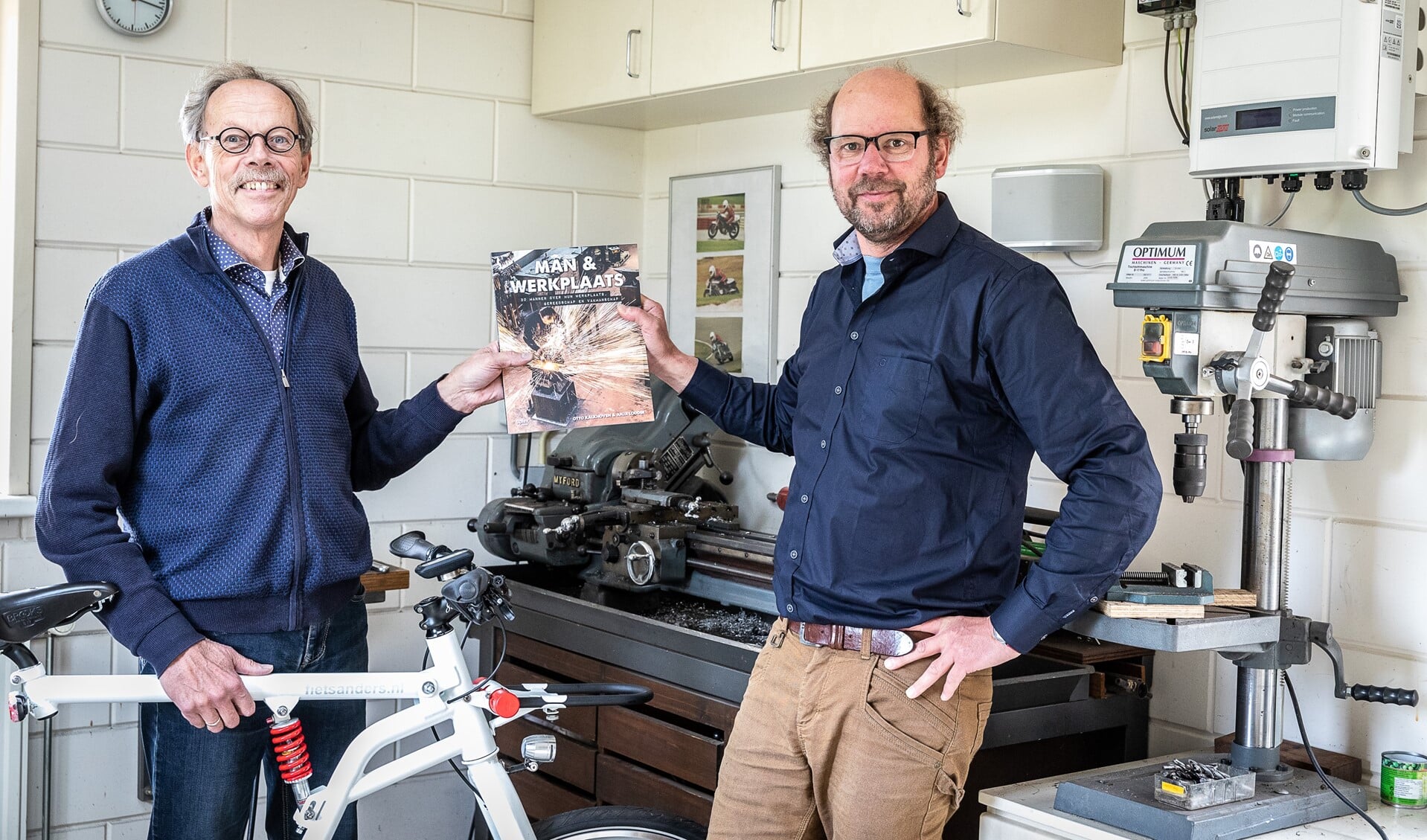 Aalt Visscher (links) ontvangt in zijn werkplaats een exemplaar van het boek namens Otto Kalkhoven 
