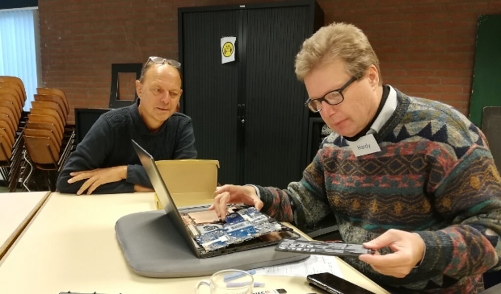 Vrijwilliger Hardy vervangt de batterij van de laptop van Wouter de Wilde