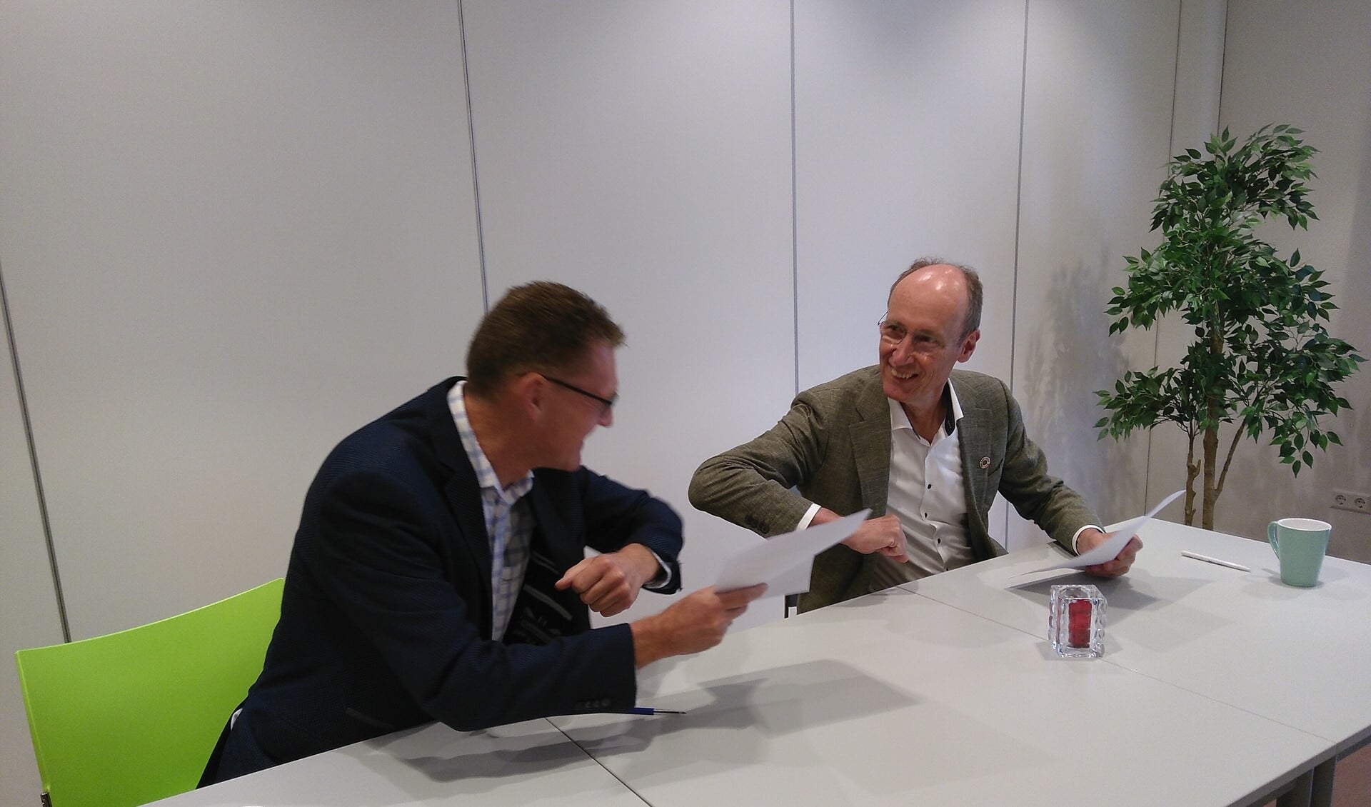 Paul Nagtegaal en Lex Hoefsloot doen elleboogstoot na ondertekening samenwerkingsovereenkomst