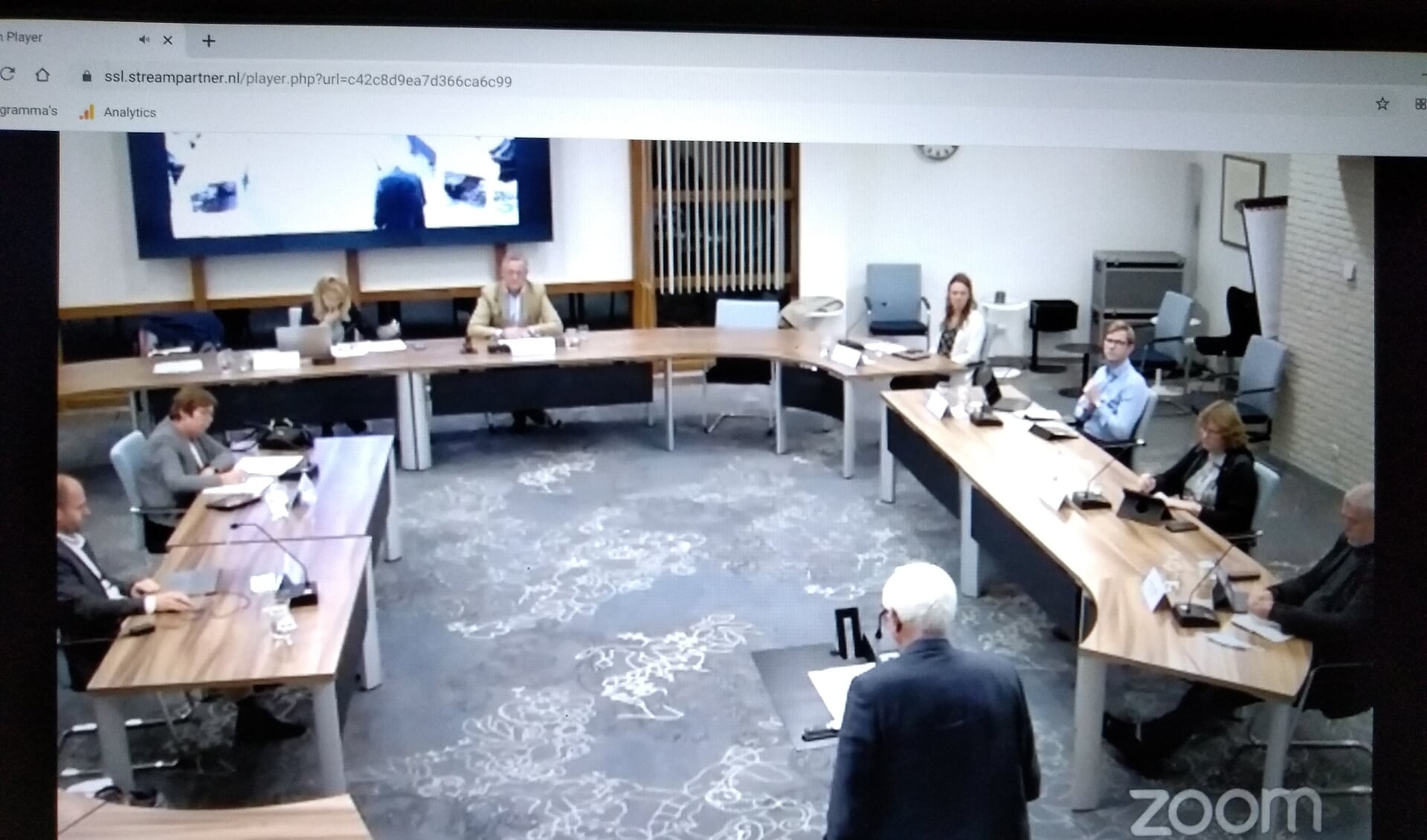 Het Open Huis via live stream, met René Walburgh Schmidt,ex-wethouder en projectontwikkelaar, op de rug gezien aan het woord. Links wethouder Ali Dekker, rechts de raadsleden.