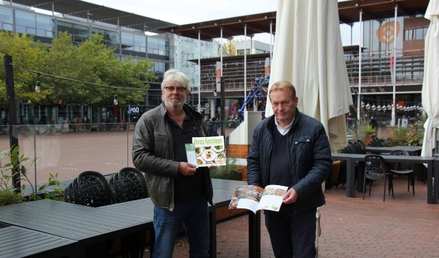 <p>Robert Mathijsen (links) en Michel Becker tonen op een gesloten terras het boek vol recepten van de lokale chefs.</p>
