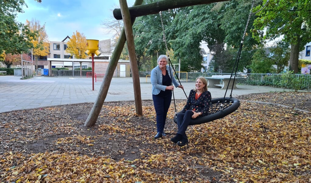 Ingeborg van Schuppen (schommel) en Susan Claessens op het gedeeltelijk groene schoolplein van de Schakel in Leersum.