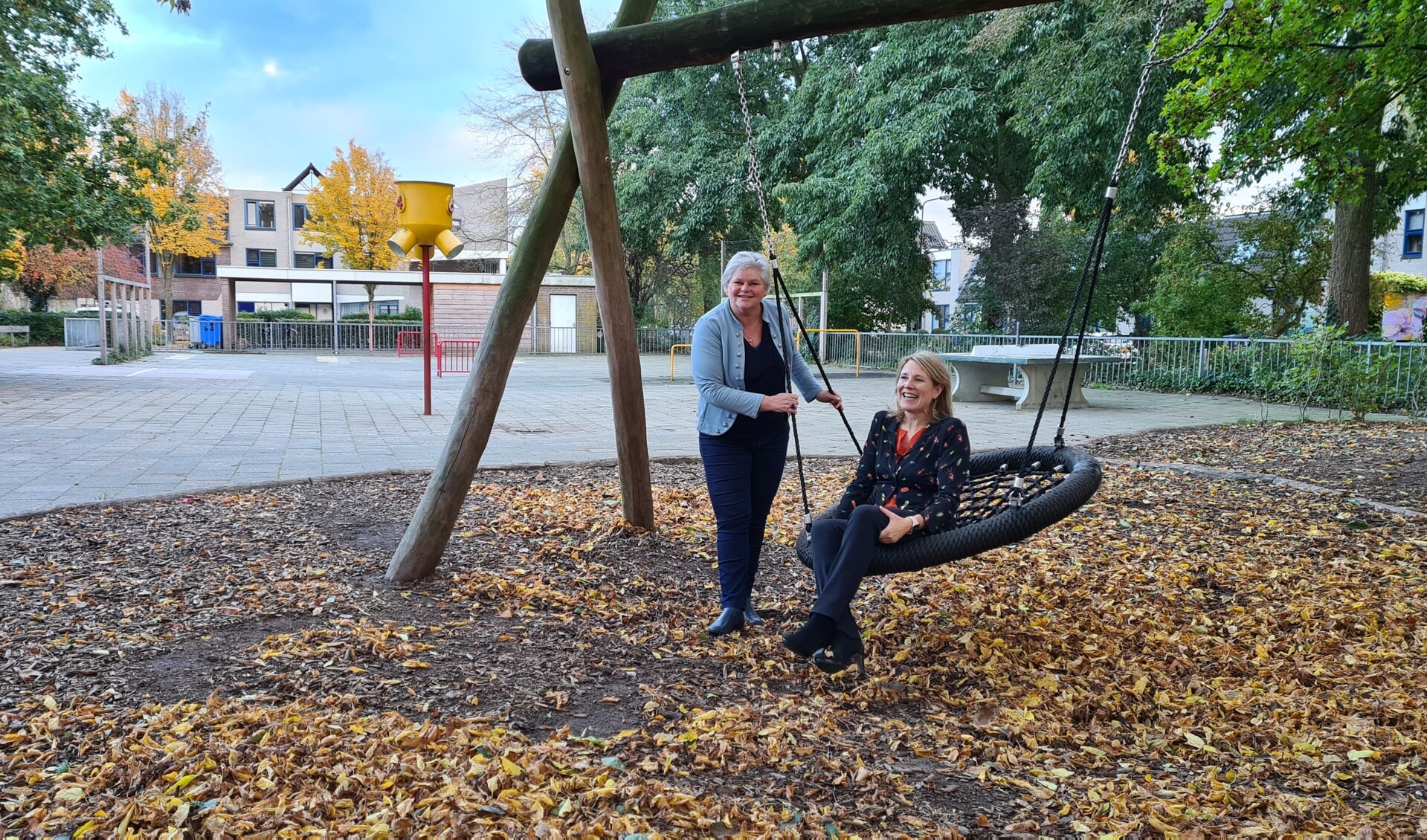 Ingeborg van Schuppen (schommel) en Susan Claessens op het gedeeltelijk groene schoolplein van de Schakel in Leersum.