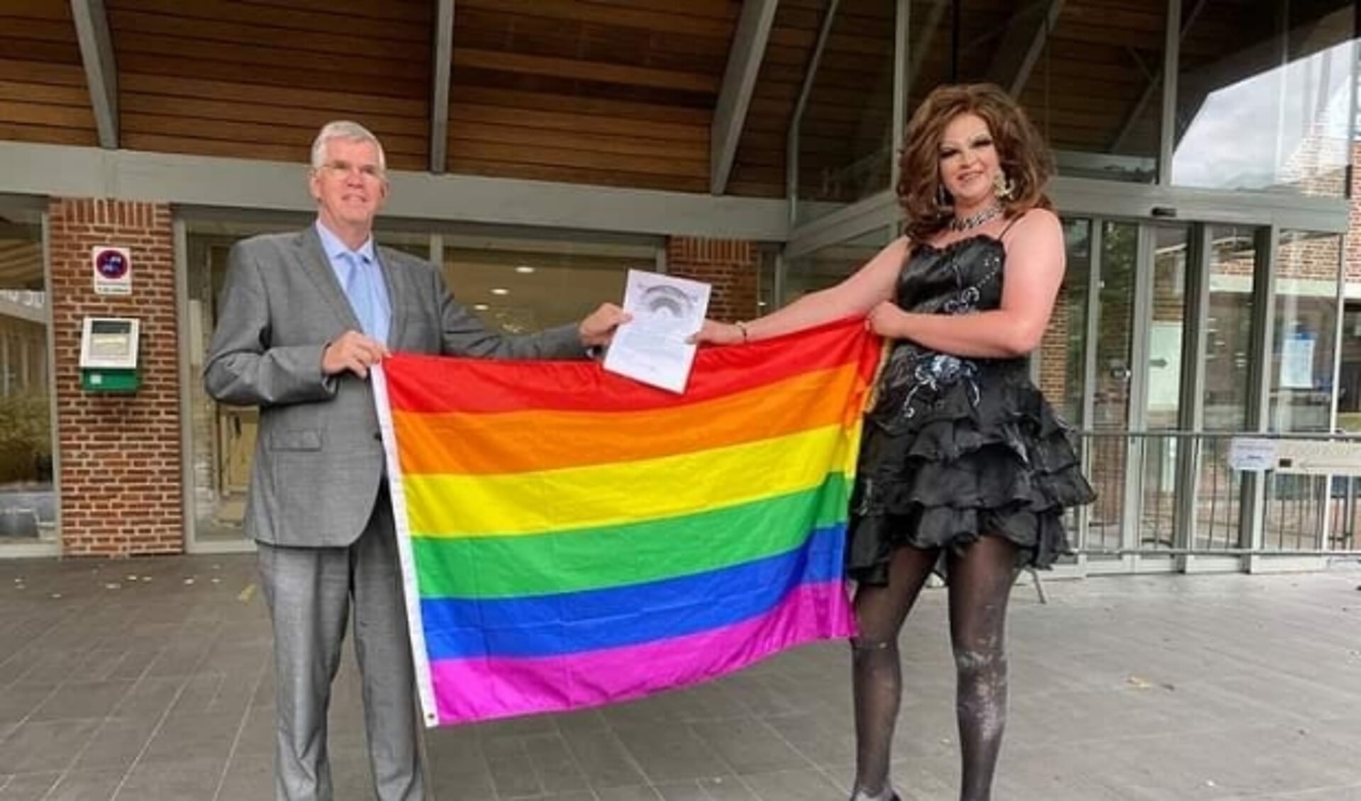 Drag queen Patty Sparkle biedt de regenboogvlag aan burgemeester Baars aan. (foto: Gemeente Ermelo)
