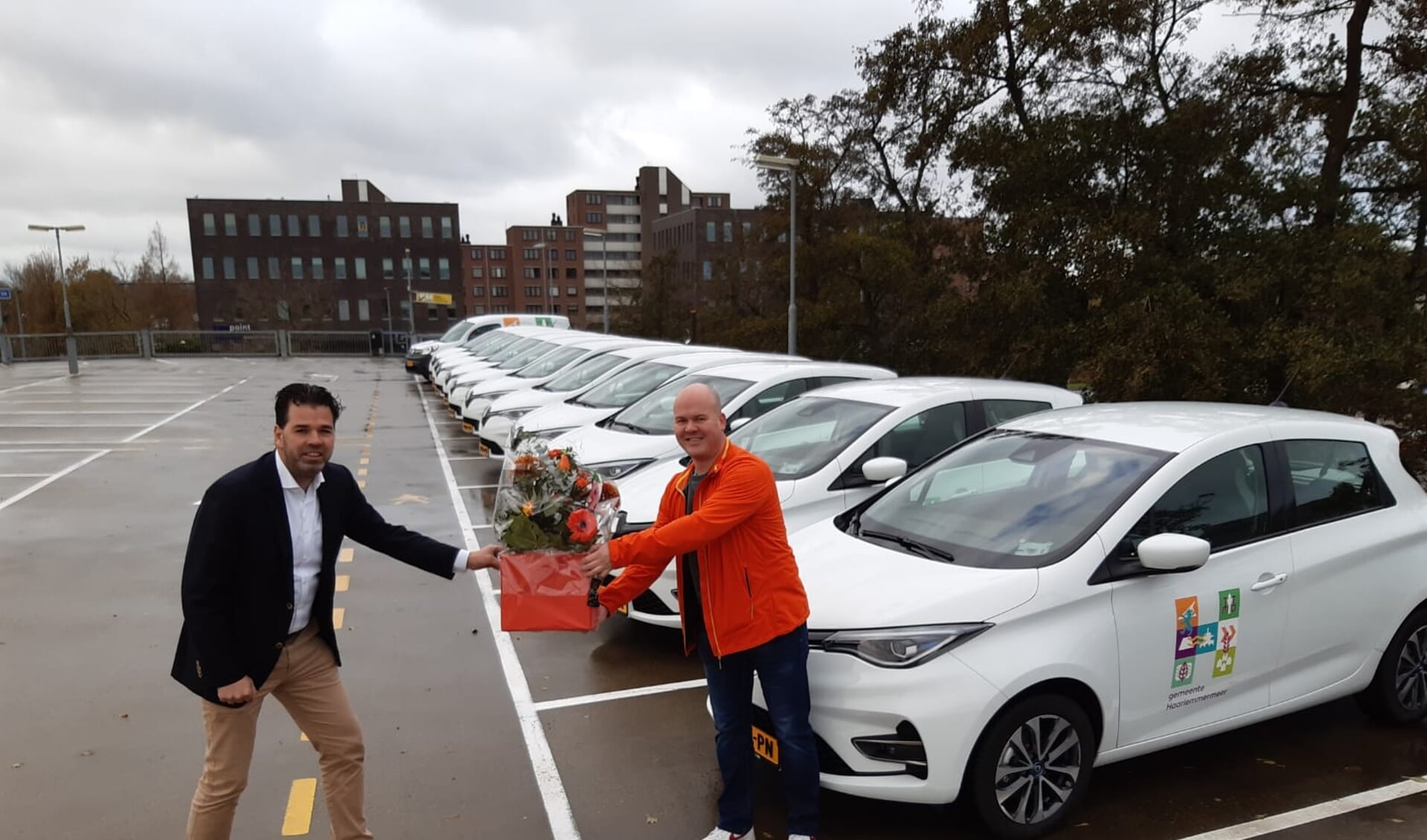 Martijn van Kampen(links) namens Renault Nieuwendijk een boeket bloemen aan Bas Rouendal van de gemeente bij de aflevering van 14 nieuwe Renaults.