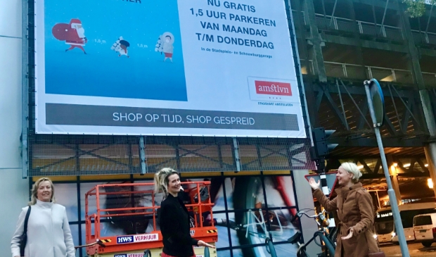 <p>Anneke van Dijk, Marlou Molenaar en Floor Gordon bij bord met oproep om op tijd inkopen te doen.</p>