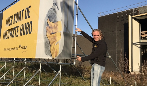 Roland Hartkamp bij het bord langs de snelweg A1 dat de komst van Hubo Hoevelaken aankondigt.