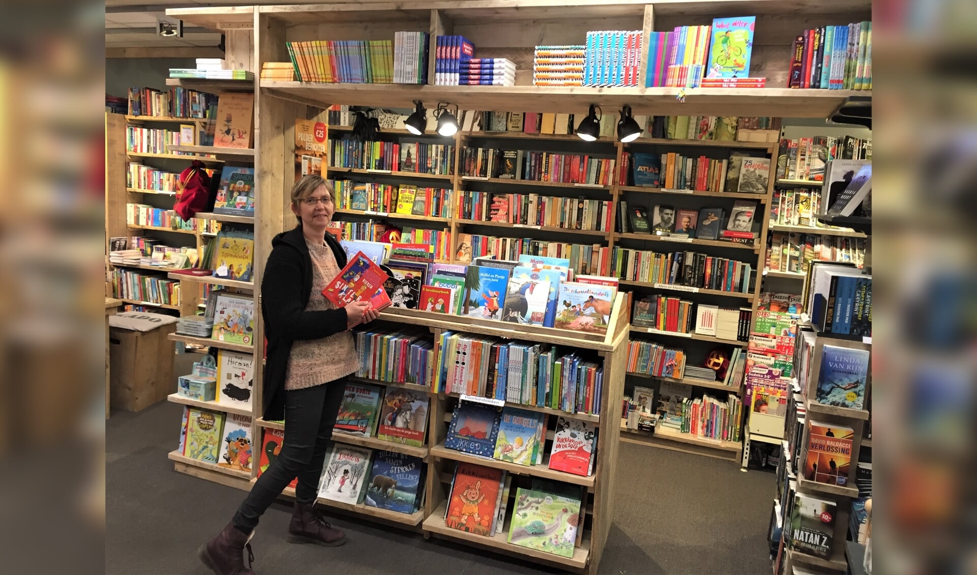 Mieke vd Boomgaard trots bij één van de nieuwe boekenkasten