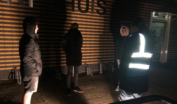 <p>Jongerenwerker Natascha, met lichtgevend hesje, op straat in gesprek met jongeren.</p>