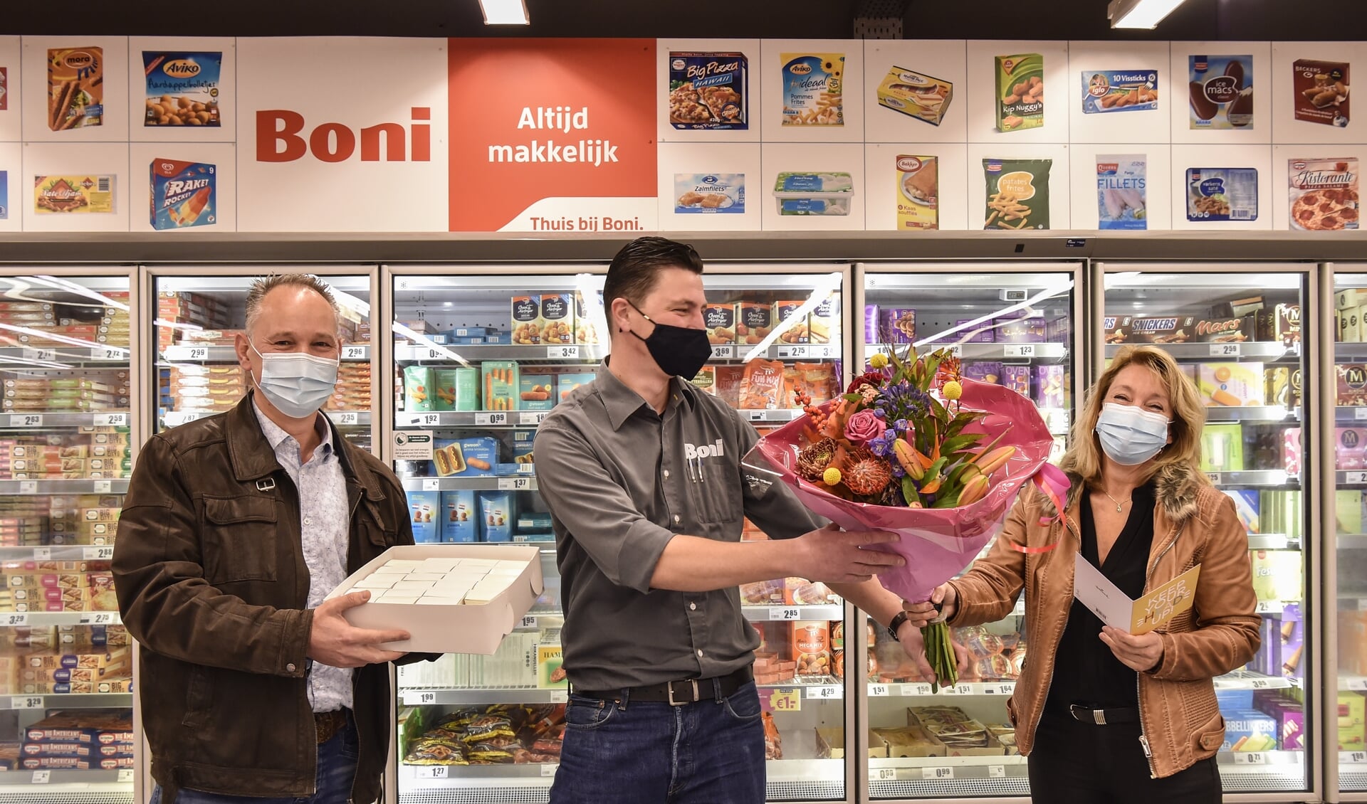 Bedrijfsleider Michel Maat (midden) neemt bloemen in ontvangst van Saskia Hop.