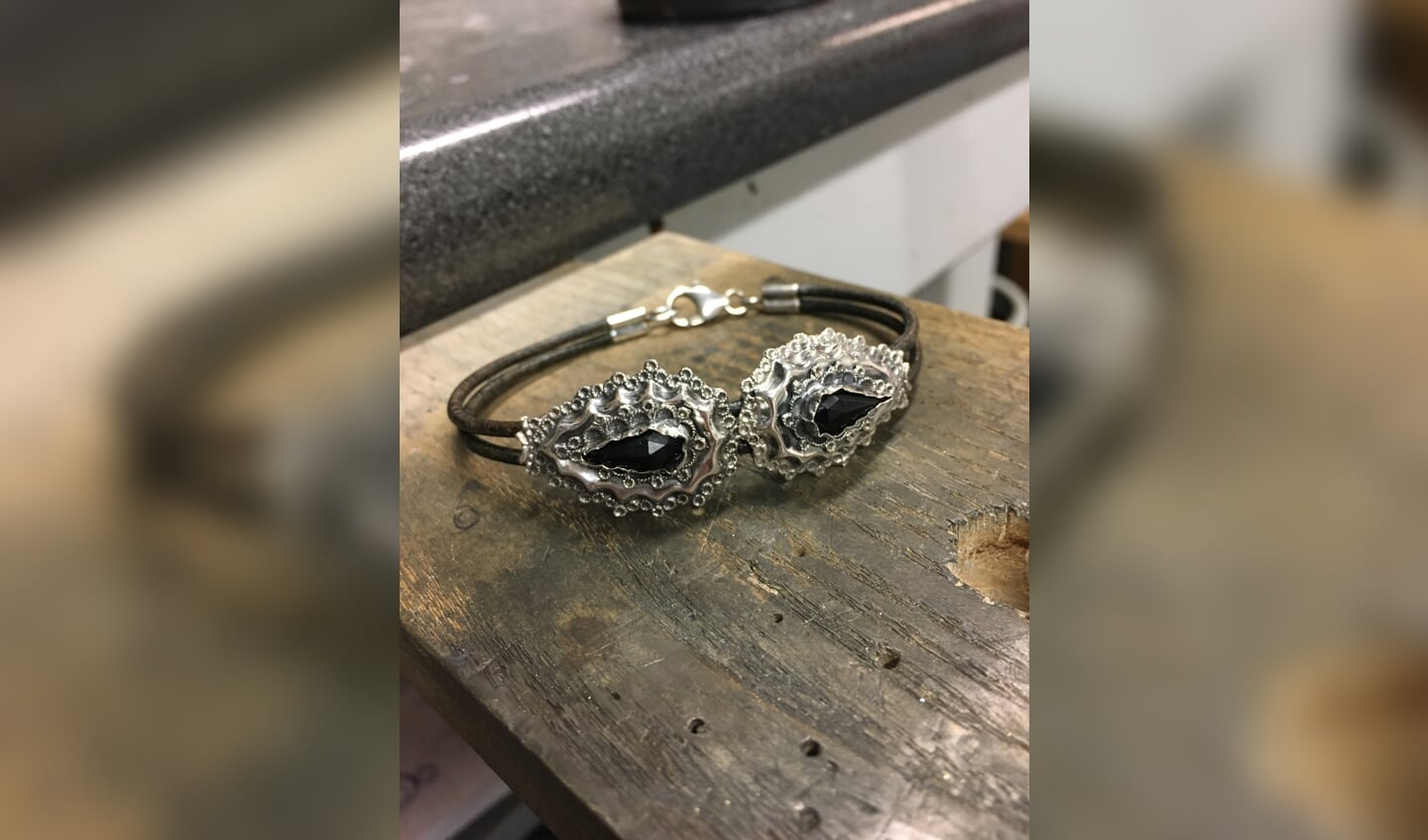 Twee oude zilveren oorbellen verwerkt in een armband met leer.