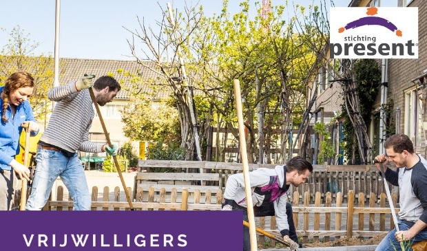 Vrijwilligers van Present werken in een tuin.
