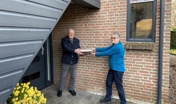 Bert van Rossum overhandigt staven en kaarten aan Wies Maas, beiden Zonnebloemvrijwilliger
