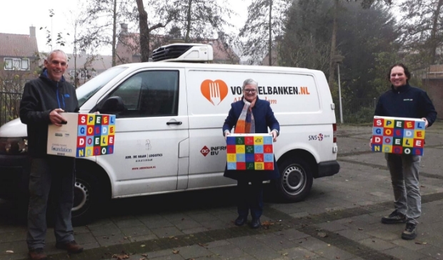 Ron van Zeggeren (bestuurslid Foundation) en Janco Romeijn (Mondial R. Vlot & Zn. Verhuizingen) overhandigen de Speelgoededoelendozen aan Anke van Veen van de Voedselbank.