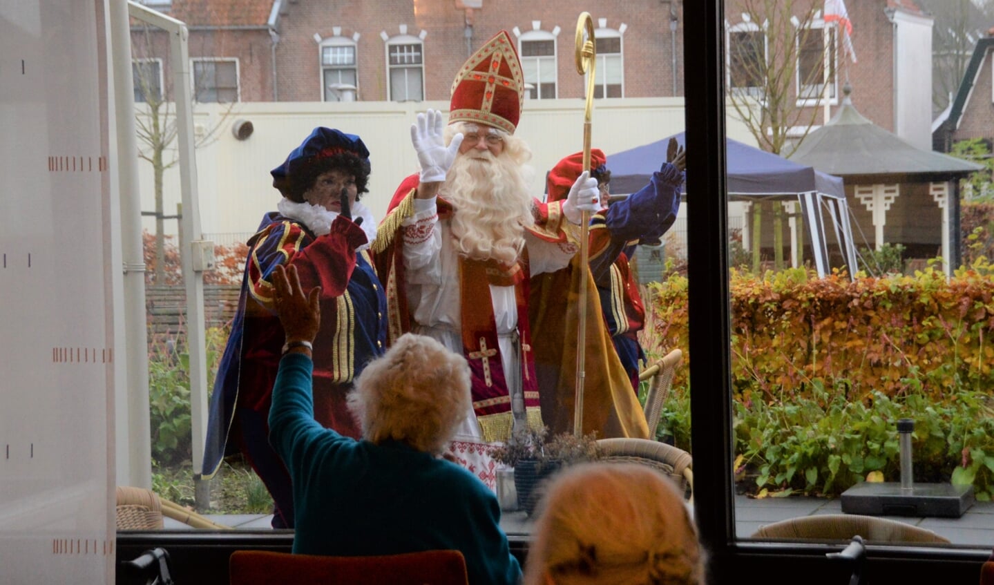 Sinterklaas en Piet zwaaiden volledig coronaproof naar de bewoners.