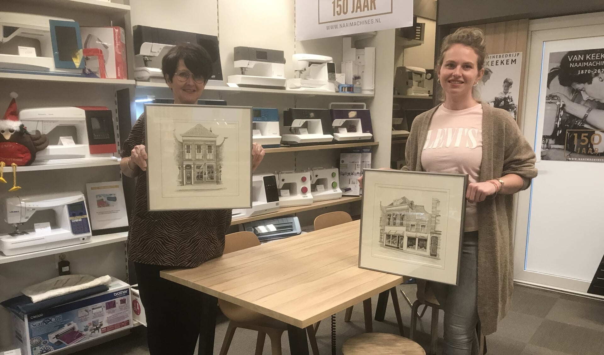 Ivonne Wildschut-van Keekem en dochter Eline met tekeningen van naaimachinewinkel door de jaren heen