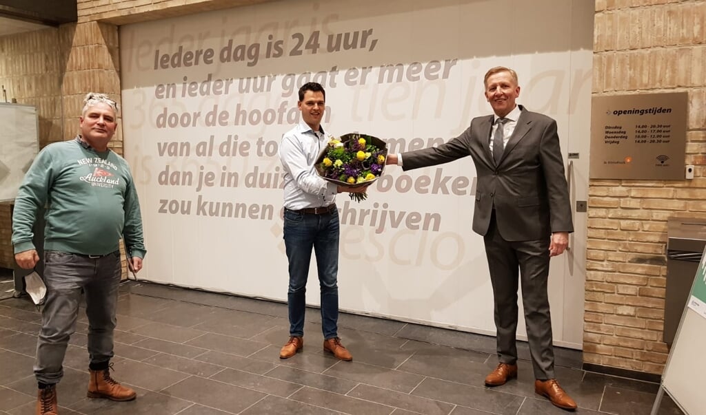Lukas Scheijgrond (CU, midden) geeft een bloemetje aan commissievoorzitter Aart van der Peut. Links PRO Scherpenzeel-leider Willem Schuur.