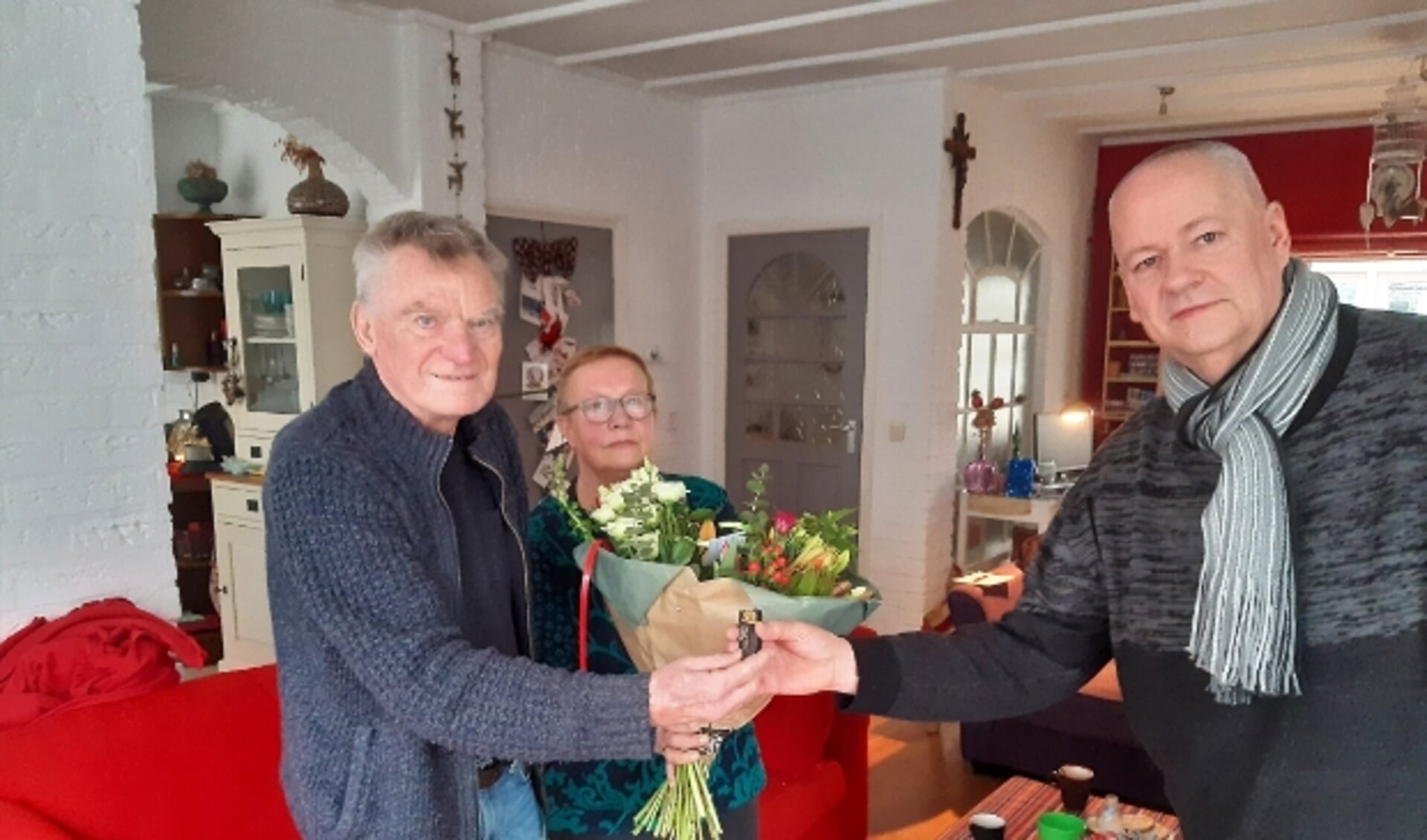 RVW-voorzitter Dick van Deest overhandigt de gouden RVW speld, voor 60 jaar trouw lidmaatschap, en bloemen aan de verraste jubilaris Wim Koenders en zijn vrouw Riet.