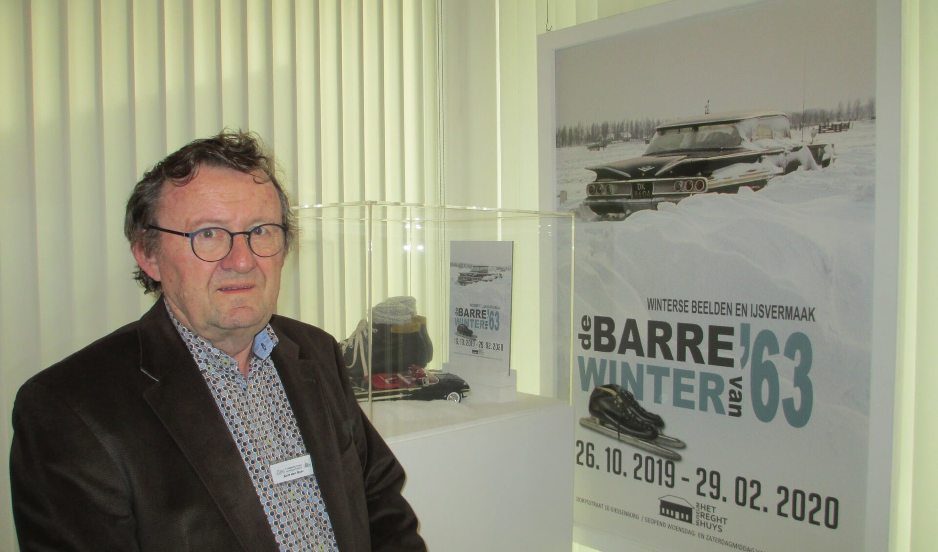 Bert den Boer bij het affiche met de ingesneeuwde taxi van Jan Rozendaal.