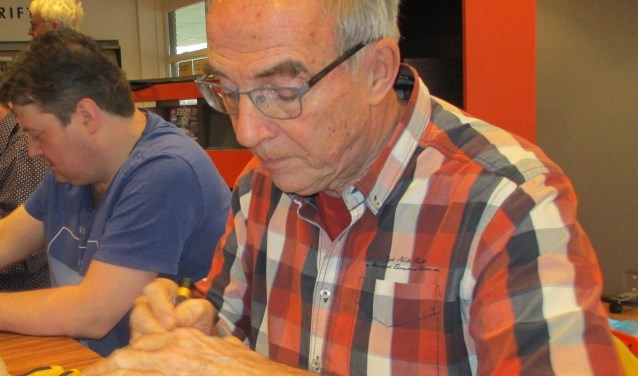 Martin Romeijn is bezig om het koffiezetapparaat van Macky Boer te repareren.