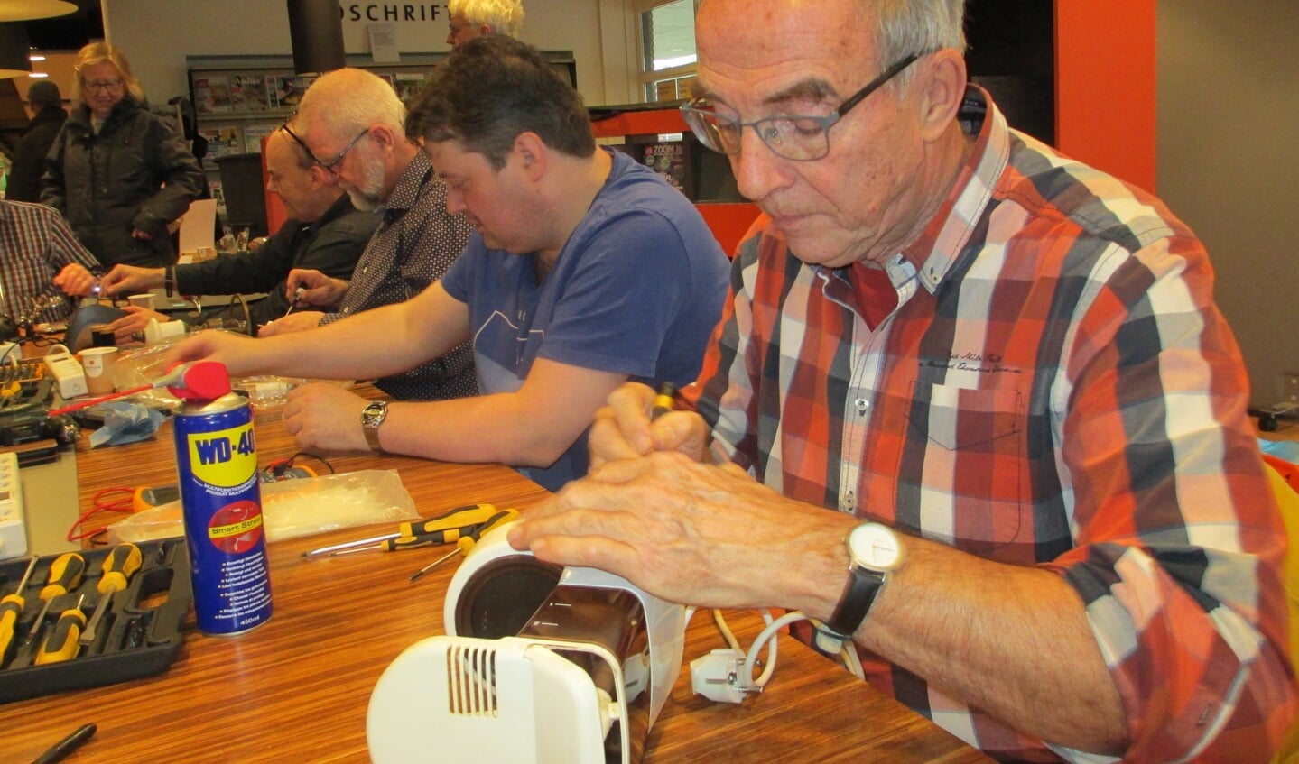 Martin Romeijn is bezig om het koffiezetapparaat van Macky Boer te repareren.