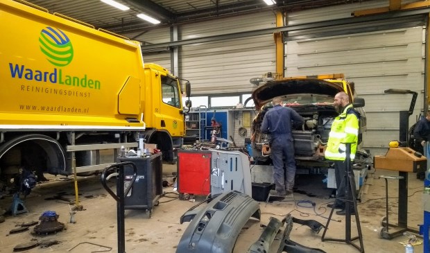 Hans van den Brule kijkt toe terwijl een van de monteurs werkt aan een auto van reinigingsdienst Waardlanden.