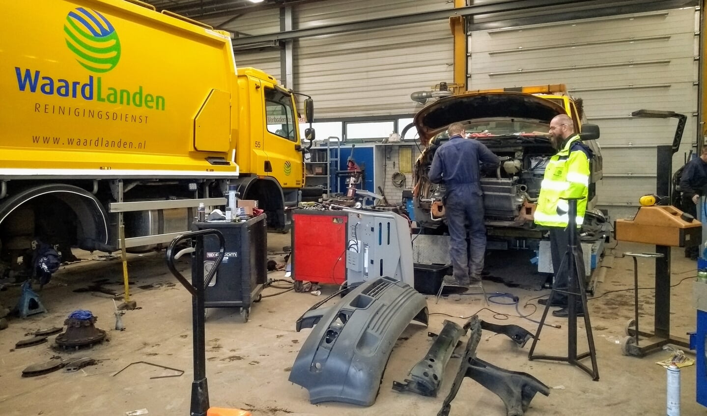 Hans van den Brule kijkt toe terwijl een van de monteurs werkt aan een auto van reinigingsdienst Waardlanden.