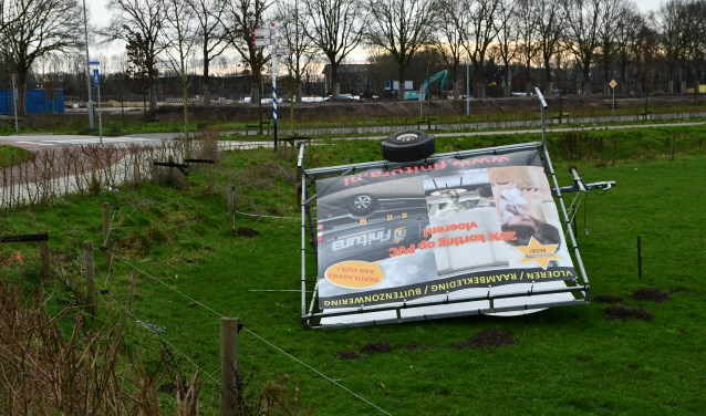 Een omgewaaide reclame-aanhanger in een weiland op de Stationsstraat.
