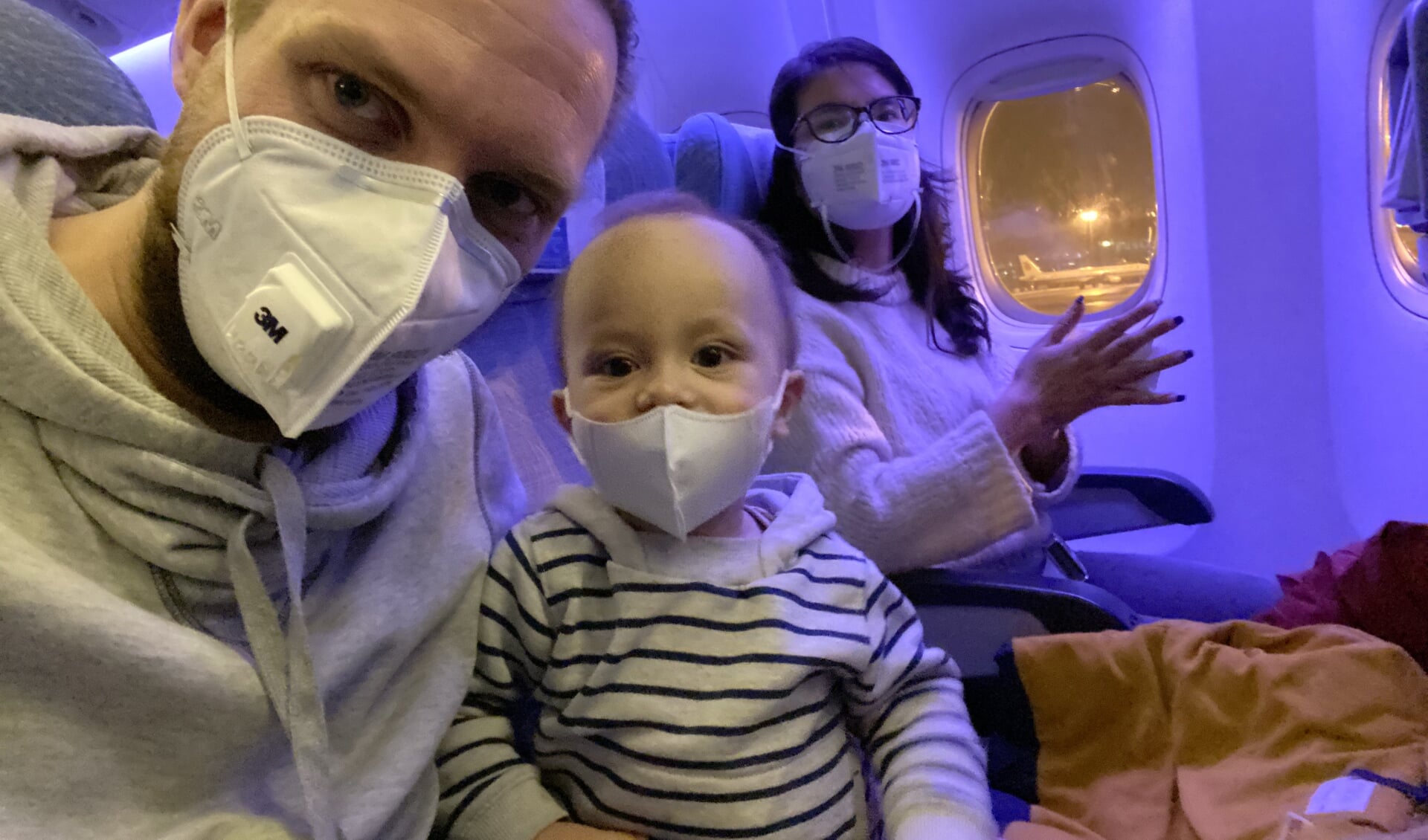 Edwin Veldhuizen, zoontje Owen en zijn vrouw JingYa met mondkapjes in het vliegtuig van China naar Nederland.