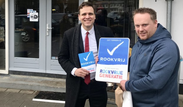 Wethouder van Ballegooijen overhandigt eigenaar Ronald Lases een rookvrij-bord.
