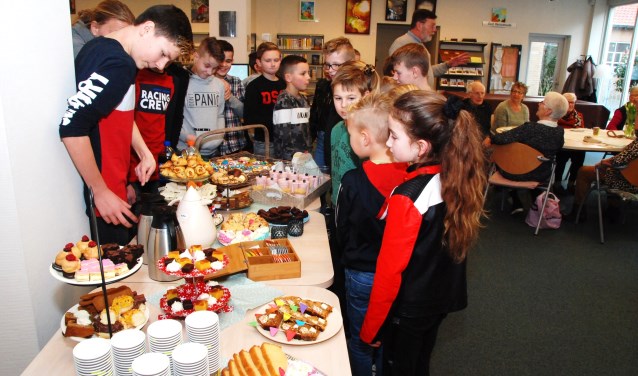 Scholieren bij de goed gevulde tafel met high tea-gerechten.