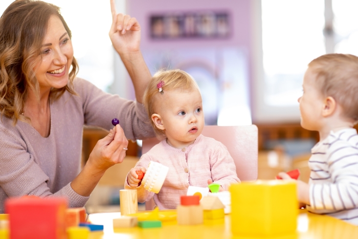 Een pedagogisch medewerker helpt kinderen op een leuke interactieve manier met de ontwikkeling van kinderen.