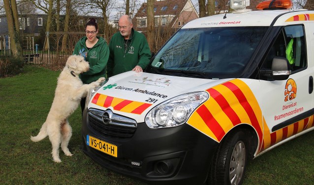 Vrijwilligers Jasmijn Strootman en Eric Vreezen met de witharige Nash bij hun dierenambulancewagen.