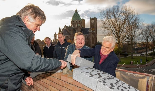 Tom van Hooijdonk (links) en Jan Aalbert (rechts) van Spaarnesant leggen de laatste steen van de Cruquiusschool.
