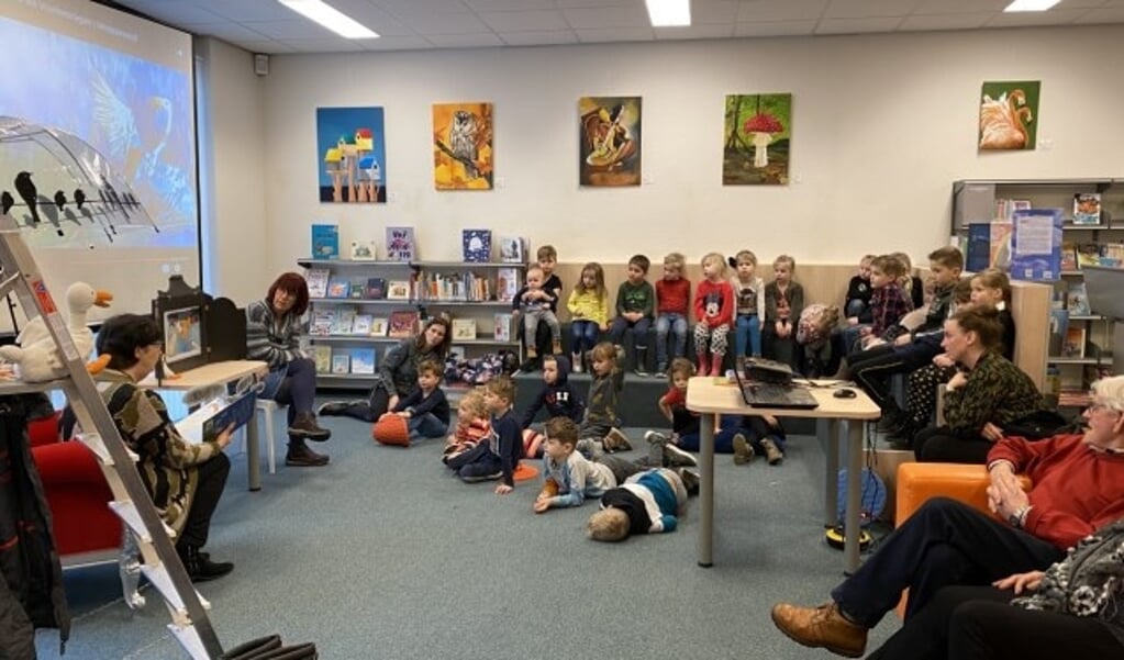 Kinderen luisteren naar juf Timmer in de bibliotheek van Renswoude.