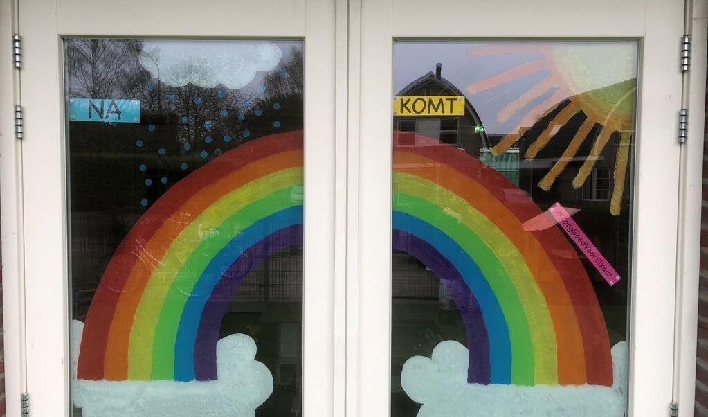 De beschilderde ramen van kinderdagverblijf De Kinderruimte aan de Molenstraat met de tekening en tekst Na regen komt zonneschijn.
