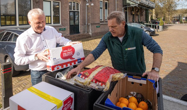 Ruud Bouwman (l) levert zijn voorraad in bij een medewerker van de Voedselbank.