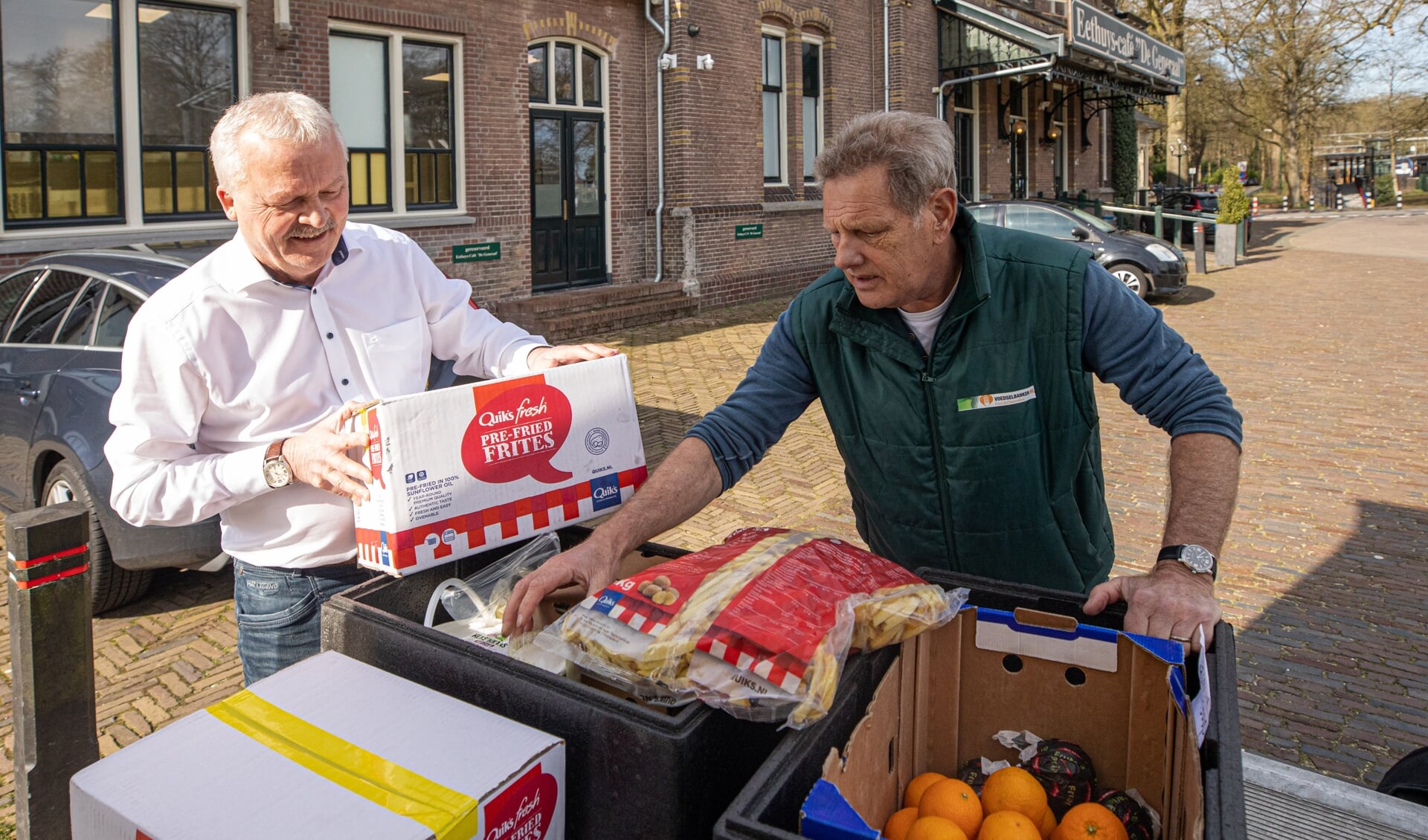Ruud Bouwman (l) levert zijn voorraad in bij een medewerker van de Voedselbank.