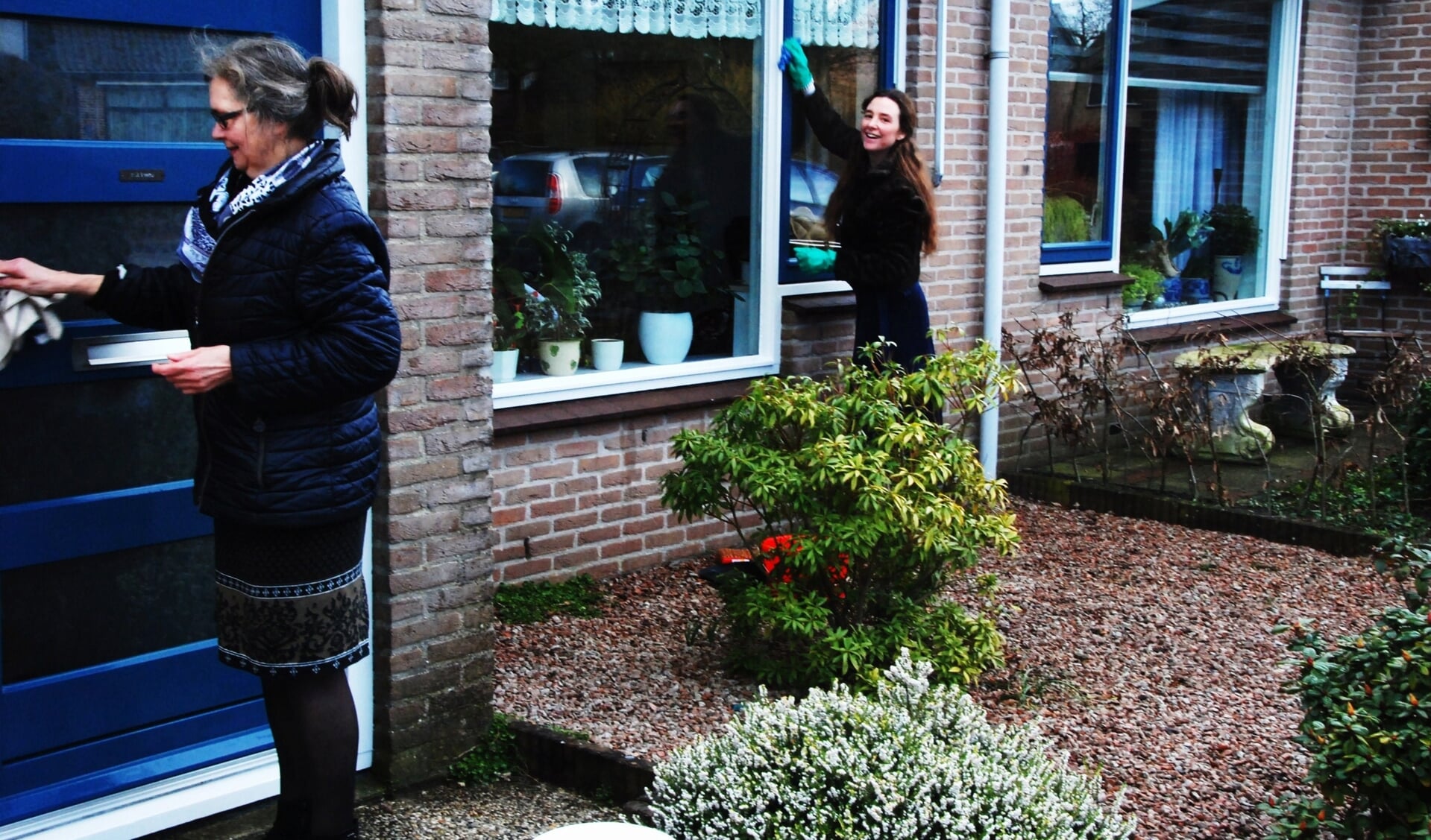 Twee vrijwilligers van de NPV reinigen het houtwerk en de ramen aan de Lijsterbeslaan tijdens NL Doet.