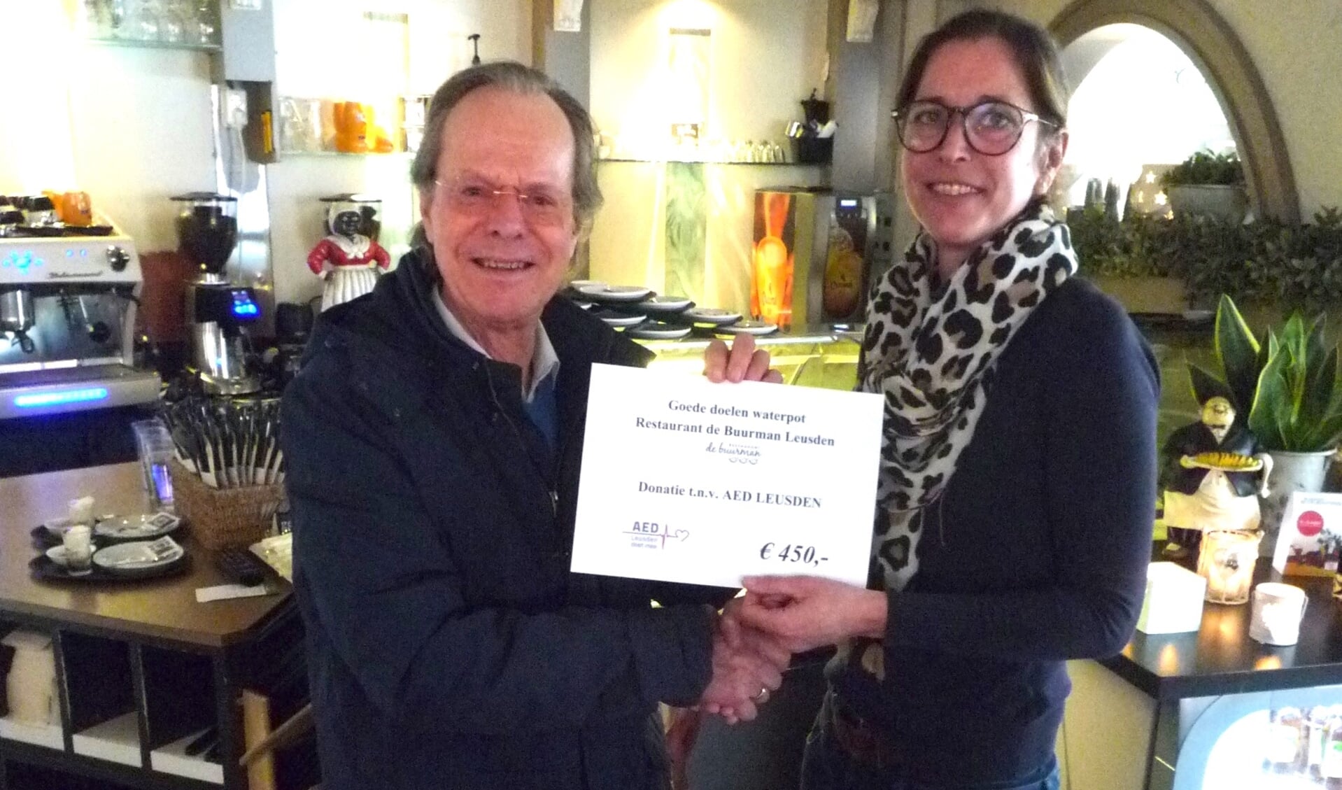 Jeff de Vries ontvangt de cheque voor een AED kast uit handen van Nadine Veeneman van restaurant de Buurman 