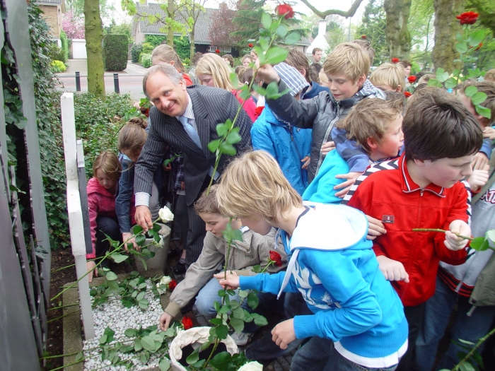 Groep 8 leerlingen leggen op 17 april 2009, onder aanvoering van wethouder Bert de Graaf, witte en rode rozen bij het Walter Strang Monument.