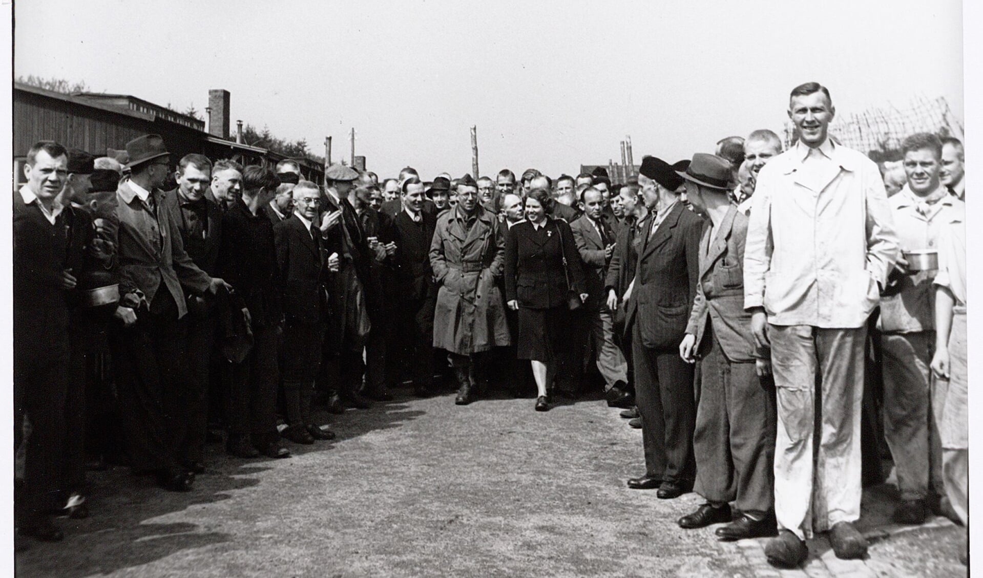 Rode Kruismedewerkster Loes van Overeem (midden) leidt de Nederlandse oorlogscorrespondent Ton van Beers rond bij de bevrijding van Kamp Amersfoort op 7 mei 1945.