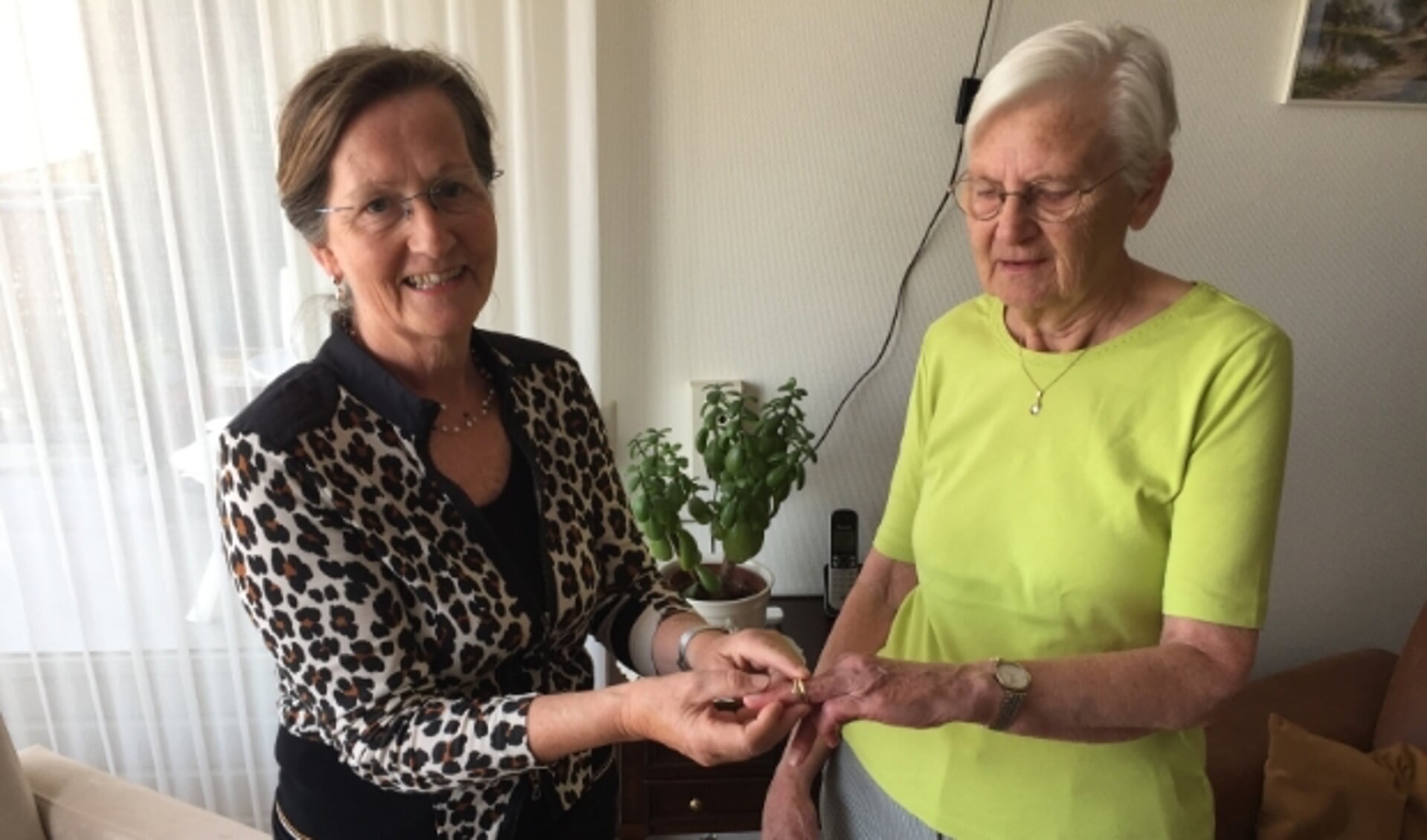 Nina Pijl schuift de ring om de vinger van Corrie van Rabenswaaij-Bos. De 81-jarige is dolblij dat ze de ring weer terug heeft. (Foto: Arie Pijl)